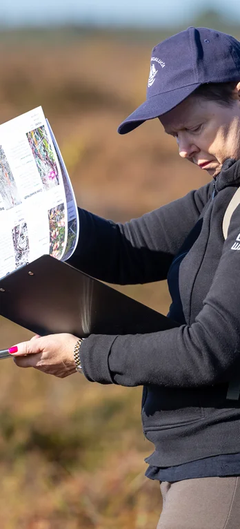 Woman completing a plant survey worksheet using her phone to record coordinates